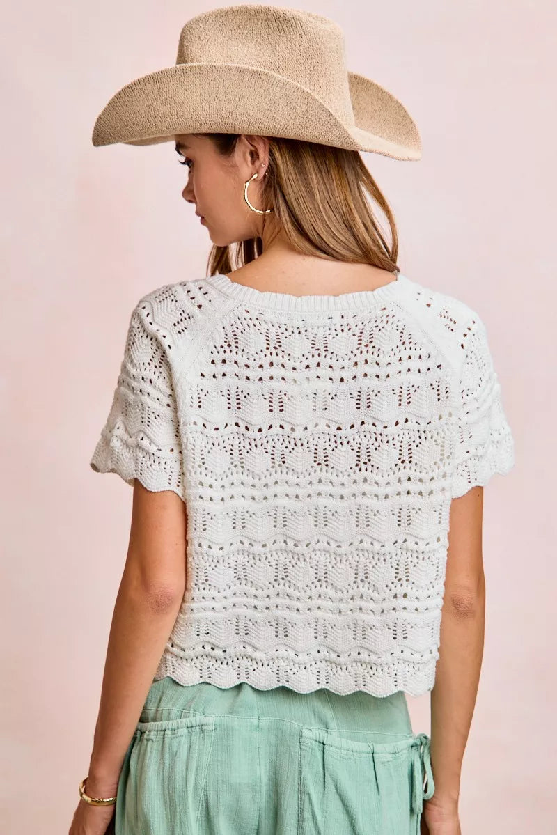 Ivory pointelle knit top with front bow tie detail from Trendsi, featuring a stylish and feminine design.