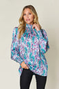 Printed smocked long sleeve blouse from Trendsi featuring a double take full size design with button closure and feminine style.