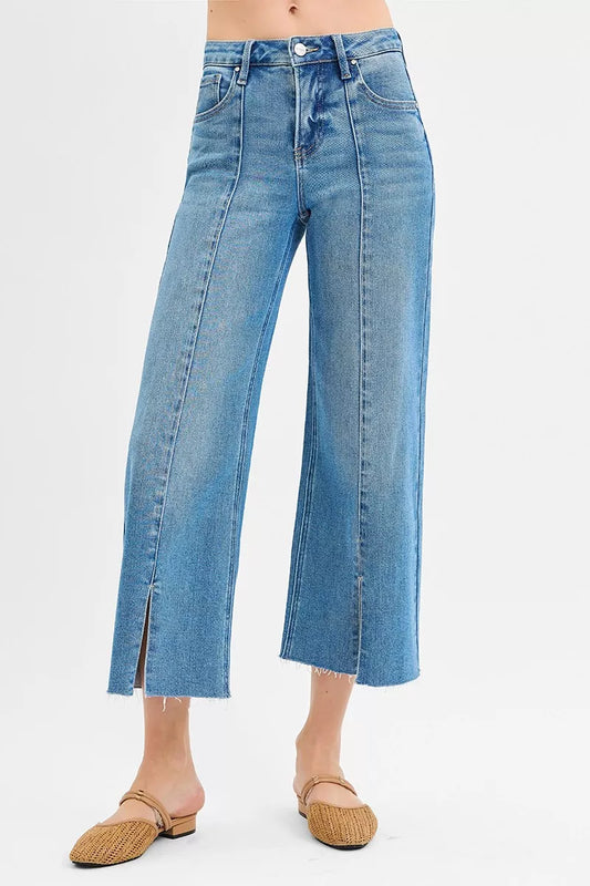 Risen Tummy Control mid-rise crop jeans with wide legs and front slit, featured in trendy denim style.