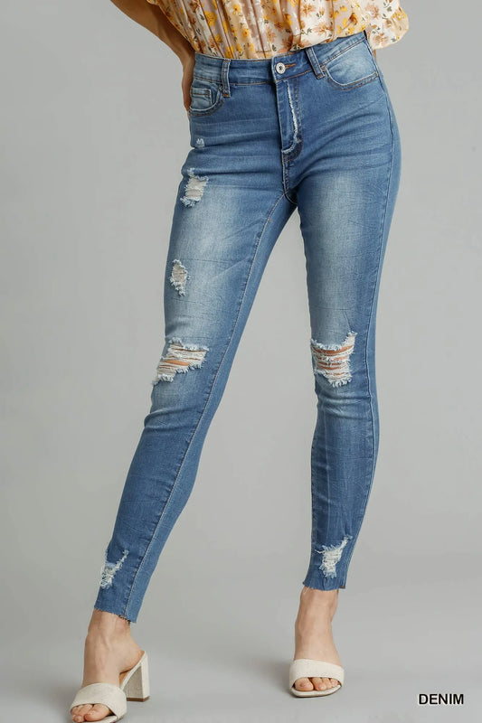 Distressed skinny jeans with edge detail by Umgee, featuring ripped accents and fitted style, shown on a model.