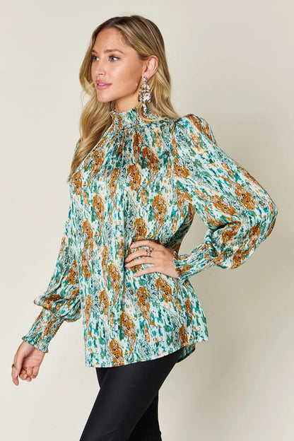 Printed smocked long sleeve blouse from Trendsi, featuring a full size, stylish design with a relaxed fit and intricate print detail.