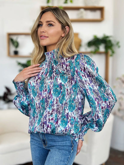 Printed smocked long sleeve blouse by Trendsi, featuring a full-size design with a stylish, gathered neckline and intricate print details.