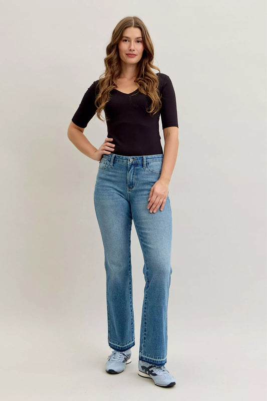 Plus size Judy Blue mid-rise slim bootcut jeans with tummy control and release hem, designed for a flattering fit.