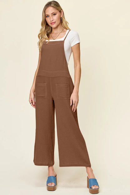 Trendsi Double Take full size textured sleeveless wide-leg overalls hanging on a rack.
