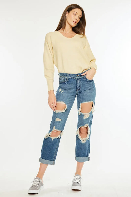 Kancan distressed mid-rise true boyfriend jeans with a relaxed fit and faded details, styled with rolled cuffs on a model.