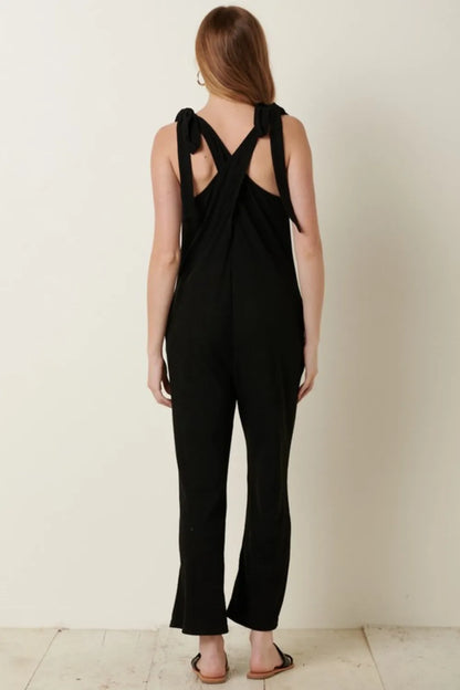 Rib knit V-neck cross back jumpsuit by Mittoshop featuring a fitted silhouette and stylish design, worn in a fashionable outdoor setting.