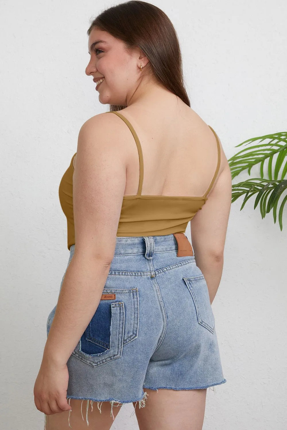 Plus size Basic Bae full size round neck slim cami by Trendsi, featuring a close-up of the black sleeveless top on a mannequin.