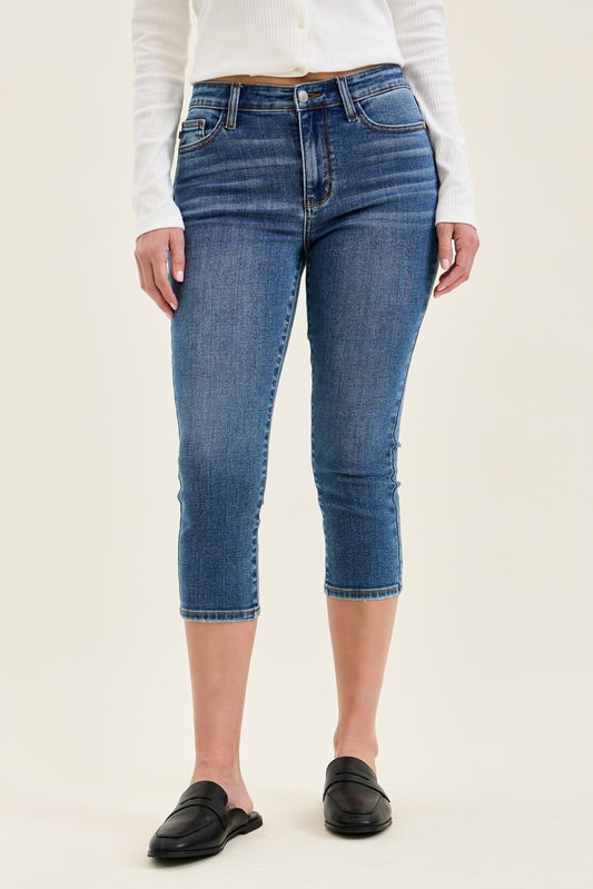 Judy Blue mid-rise stretch Capri jeans in classic denim, showcasing fitted style and rolled hems on a clean background.