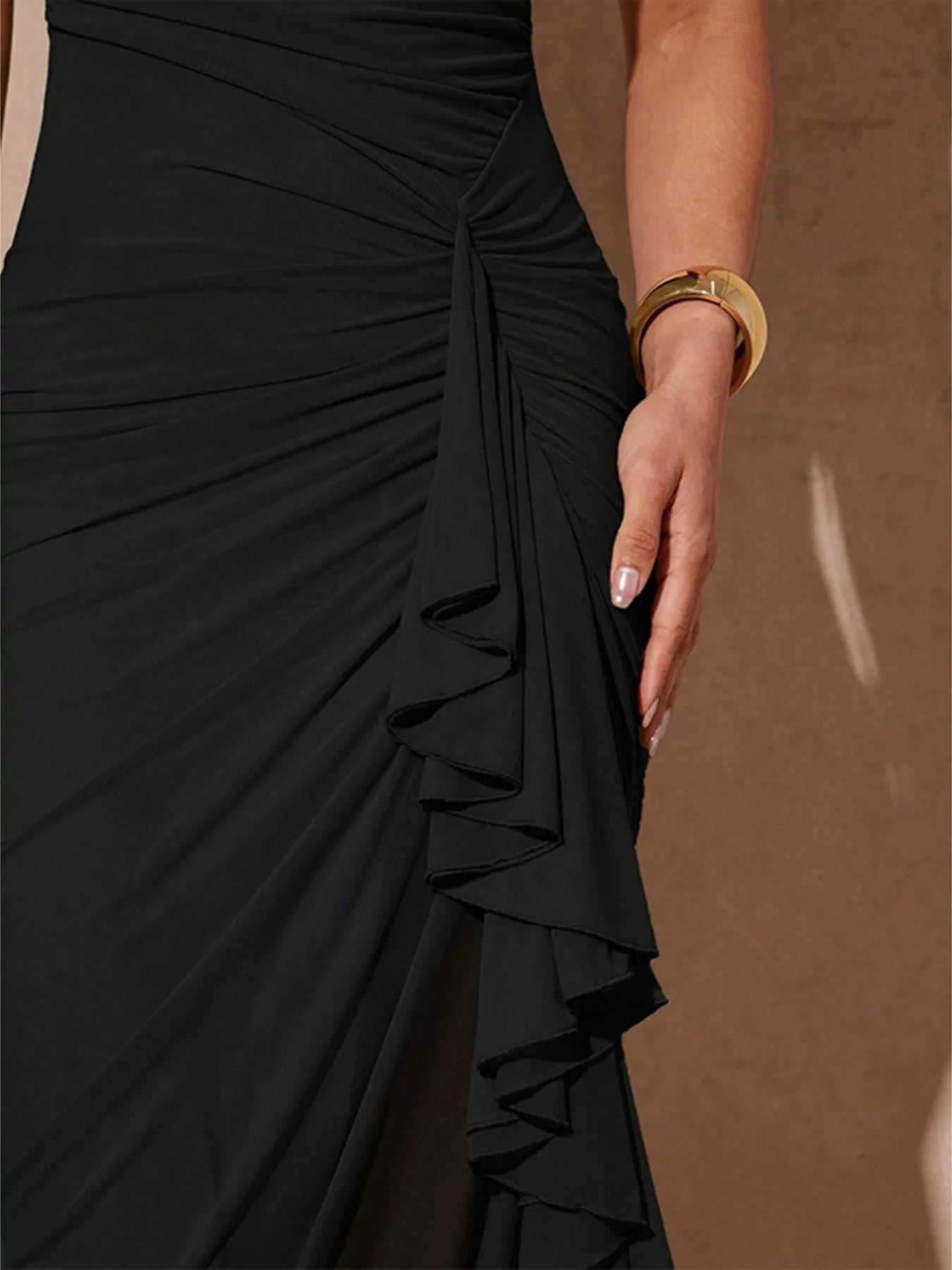 Black slit asymmetrical hem spaghetti strap maxi dress by Trendsi, featuring a flowing silhouette and stylish design.