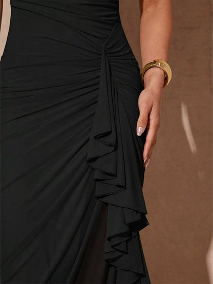 Black slit asymmetrical hem spaghetti strap maxi dress by Trendsi, featuring a flowing silhouette and stylish design.