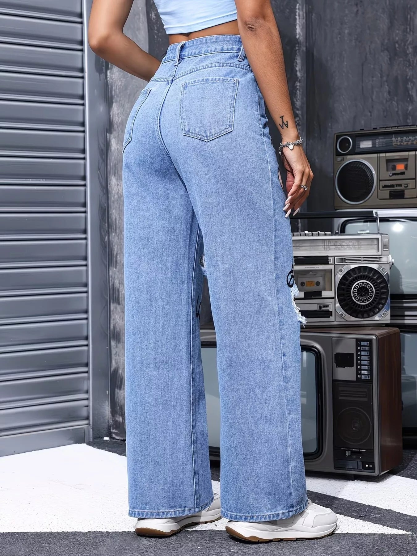 Blue distressed printed wide leg jeans from Trendsi with a relaxed fit and fashionable design, shown on a model.