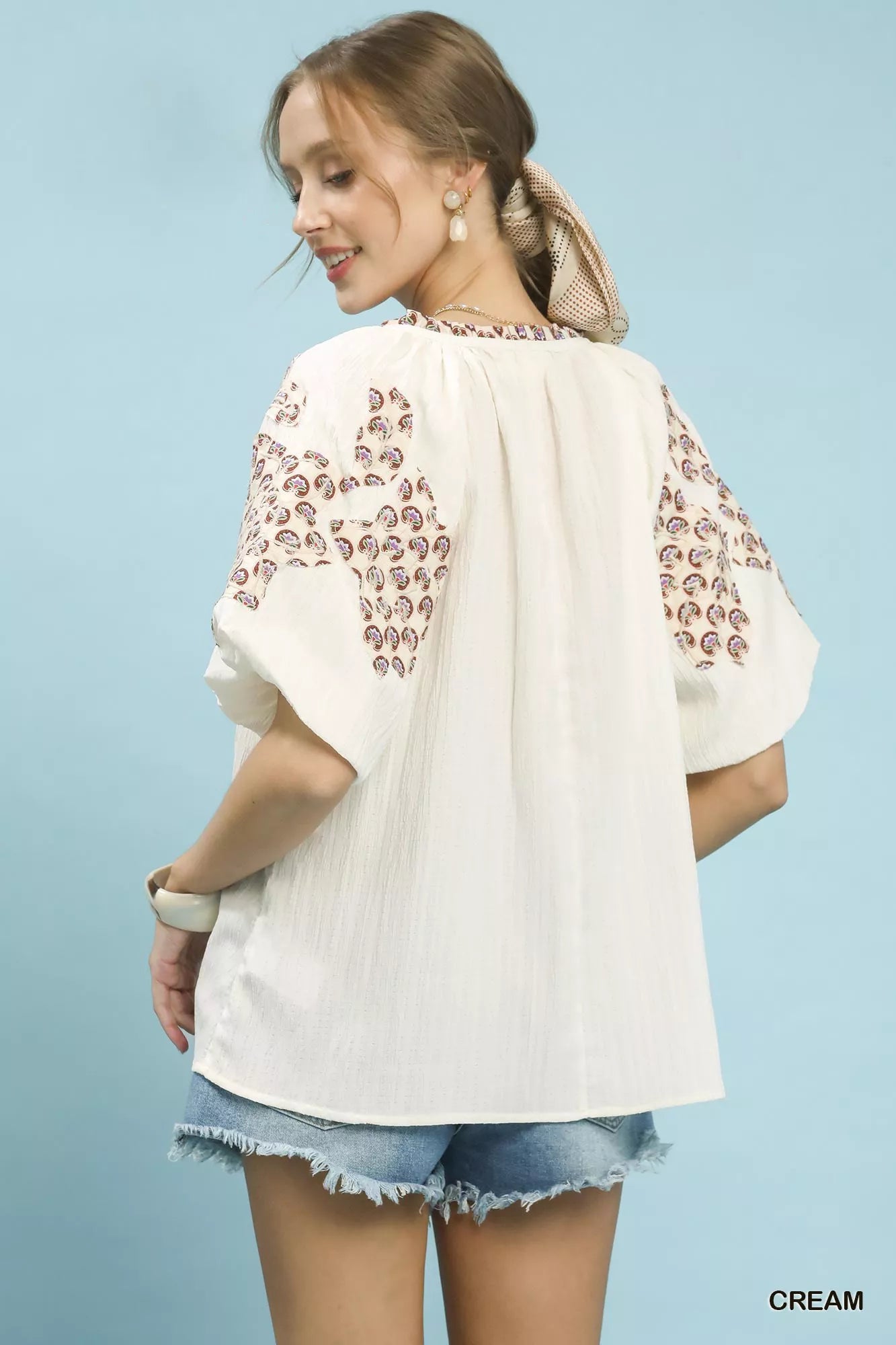 Cream Umgee embroidered sleeve contrast trim top with embroidered details and contrasting trim on sleeves.