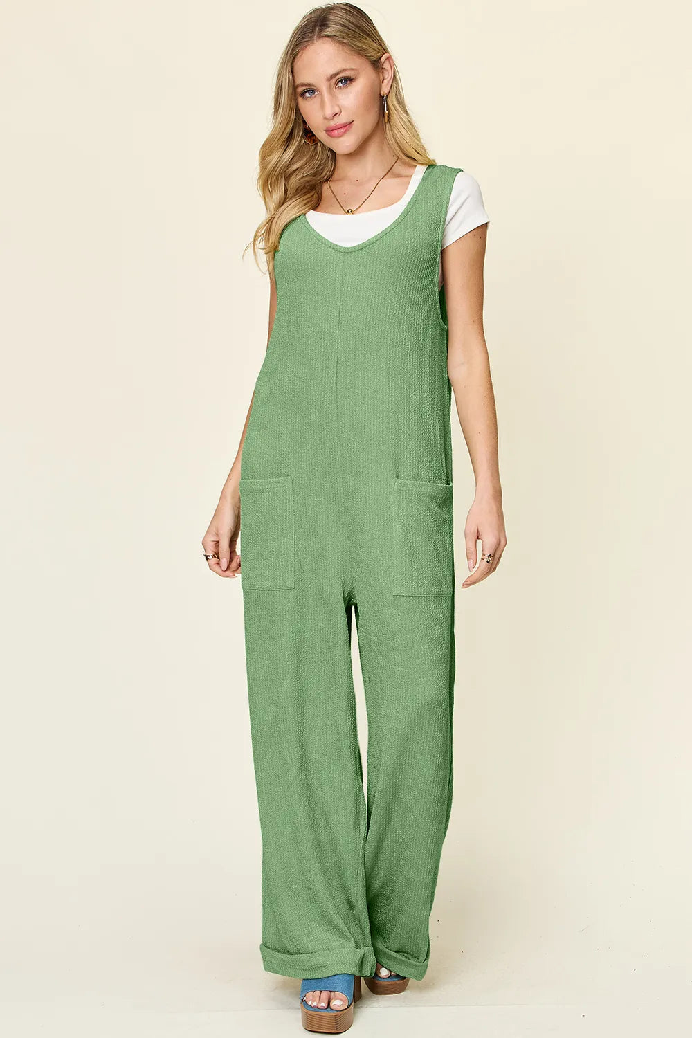 Trendsi Double Take full size textured sleeveless wide-leg jumpsuit displayed on a hanger, showcasing its stylish design and fabric details.