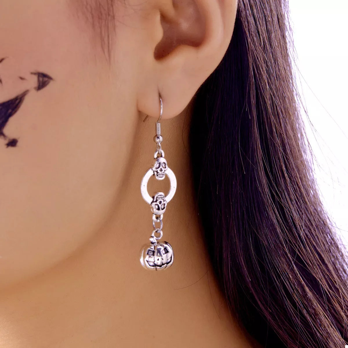 Halloween pumpkin dangle earrings by Trendsi featuring orange pumpkin charms with black accents on silver hooks.