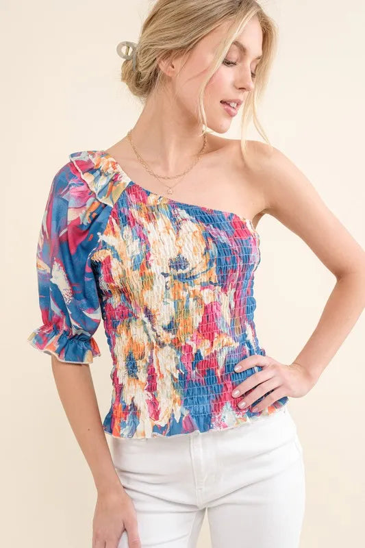 Allover floral print smocked one-shoulder blouse by Trendsi, featuring vibrant floral pattern and feminine design.