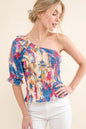 Allover floral print smocked one-shoulder blouse by Trendsi, featuring vibrant floral pattern and feminine design.