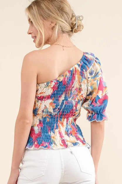 Floral print smocked one-shoulder blouse by Trendsi featuring allover colorful floral pattern and ruffled details.