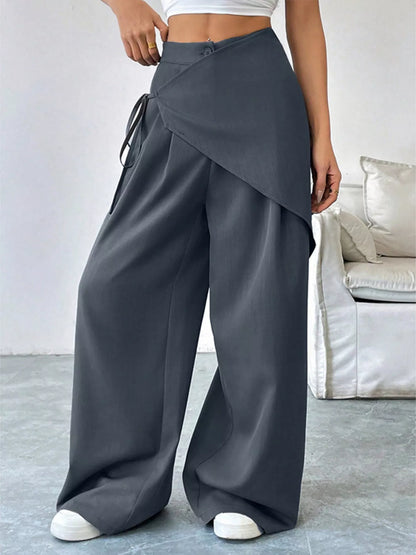 Gray asymmetrical wrap wide-leg pants by Trendsi, shown on a model, featuring flowing fabric and stylish design.