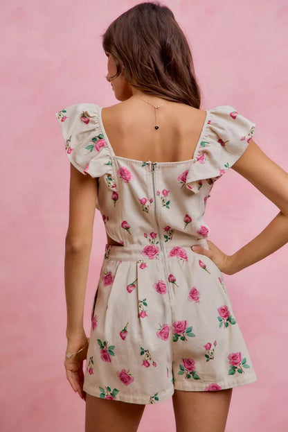Ivory-pink floral print denim romper with cut-out waist and ruffled details, featuring a stylish and trendy design.