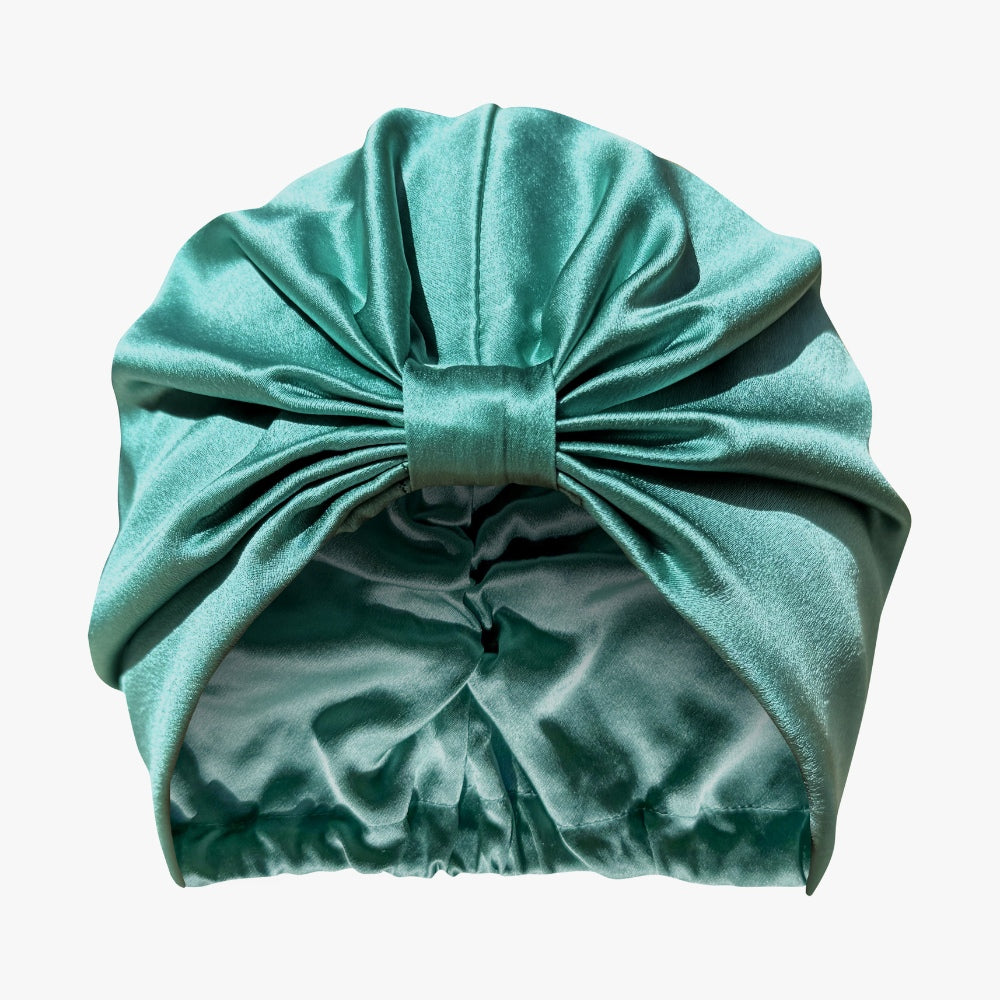 Organic silk hair bonnet by LINA LENNOX in jade green, shown lying flat with smooth, shiny fabric.