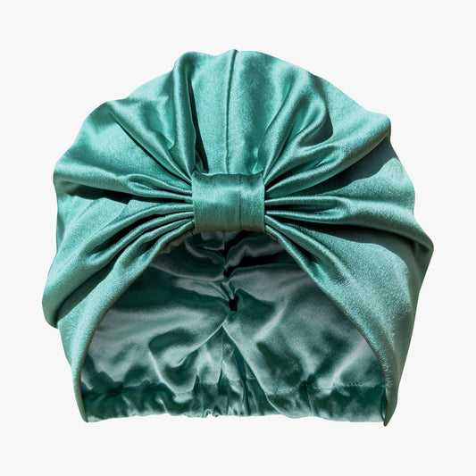 Organic silk hair bonnet by LINA LENNOX in jade green, shown lying flat with smooth, shiny fabric.