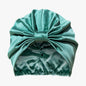 Organic silk hair bonnet by LINA LENNOX in jade green, shown lying flat with smooth, shiny fabric.