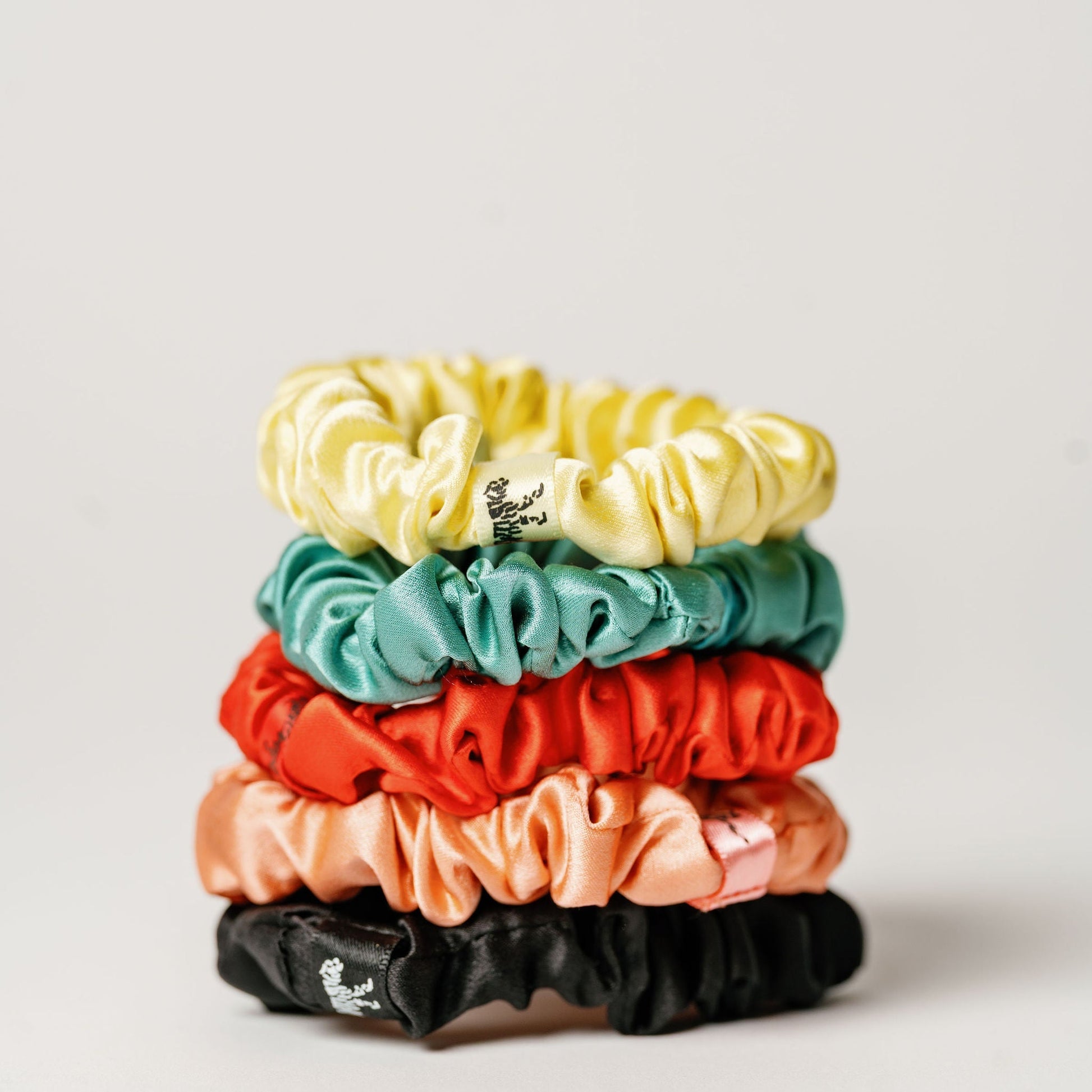 Organic silk small scrunchie in tomato red by LINA LENNOX, showcasing its soft, shiny texture and gentle elastic hold.