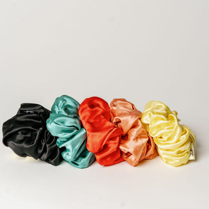 Oversized black organic silk scrunchie by LINA LENNOX, shown on a model's hair for a soft, luxurious look.