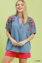 Light wash denim puff sleeve top by Umgee featuring intricate embroidery and a relaxed fit.
