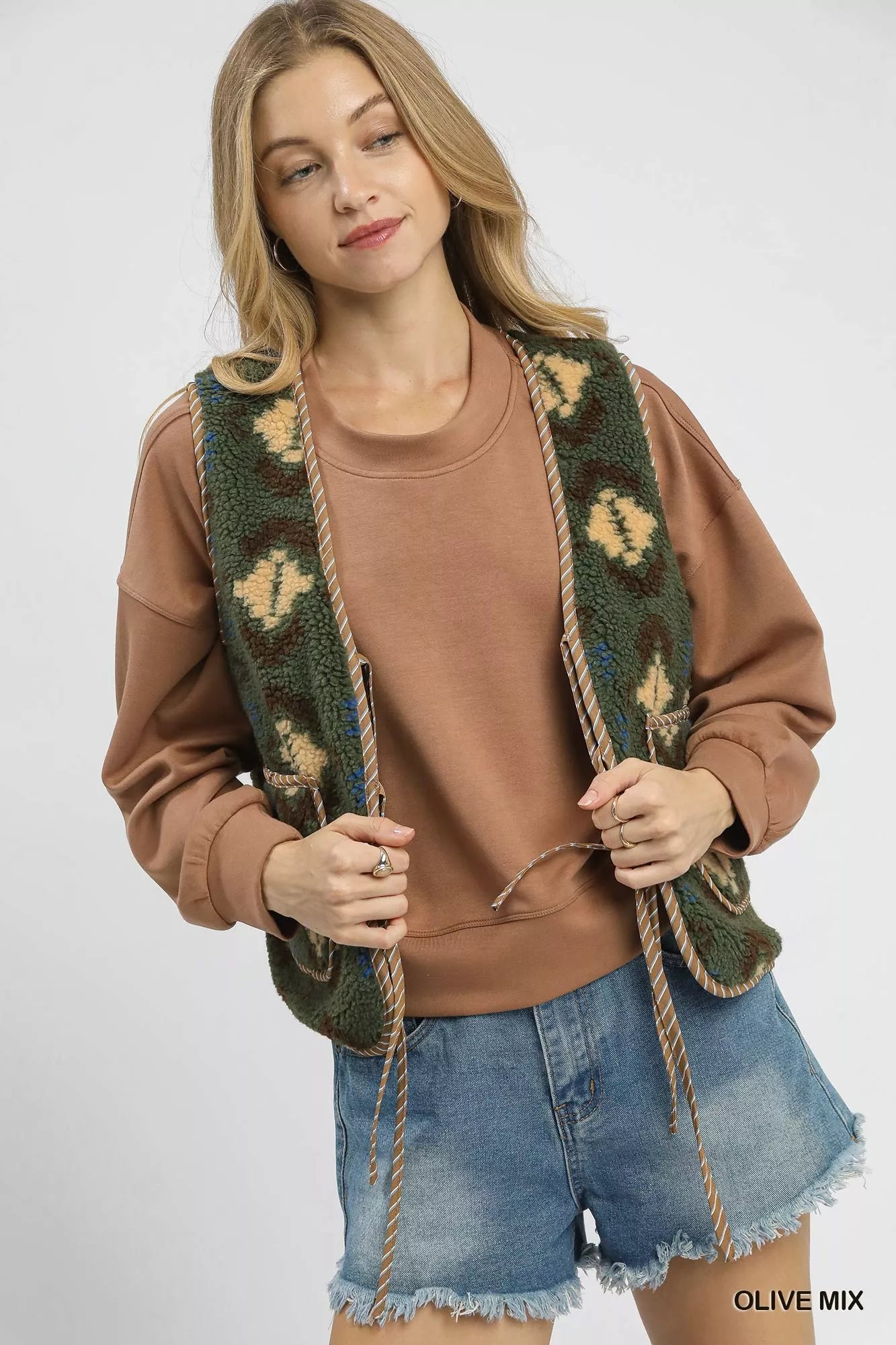 Olive green Umgee patterned Sherpa vest with tie front and mixed fabric design, styled for casual wear.