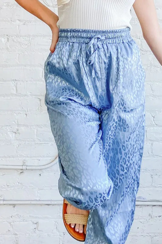 Pale blue satin leopard print joggers from And The Why by Trendsi, featuring a relaxed fit and stylish animal print design.