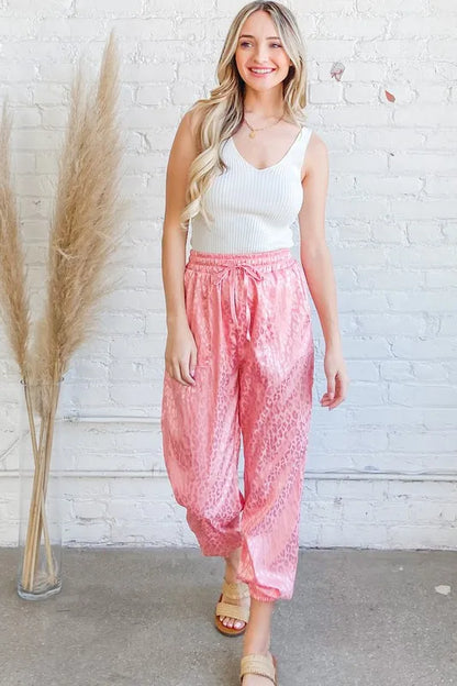 Pink satin leopard print joggers from Trendsi featuring a relaxed fit and stylish pattern.