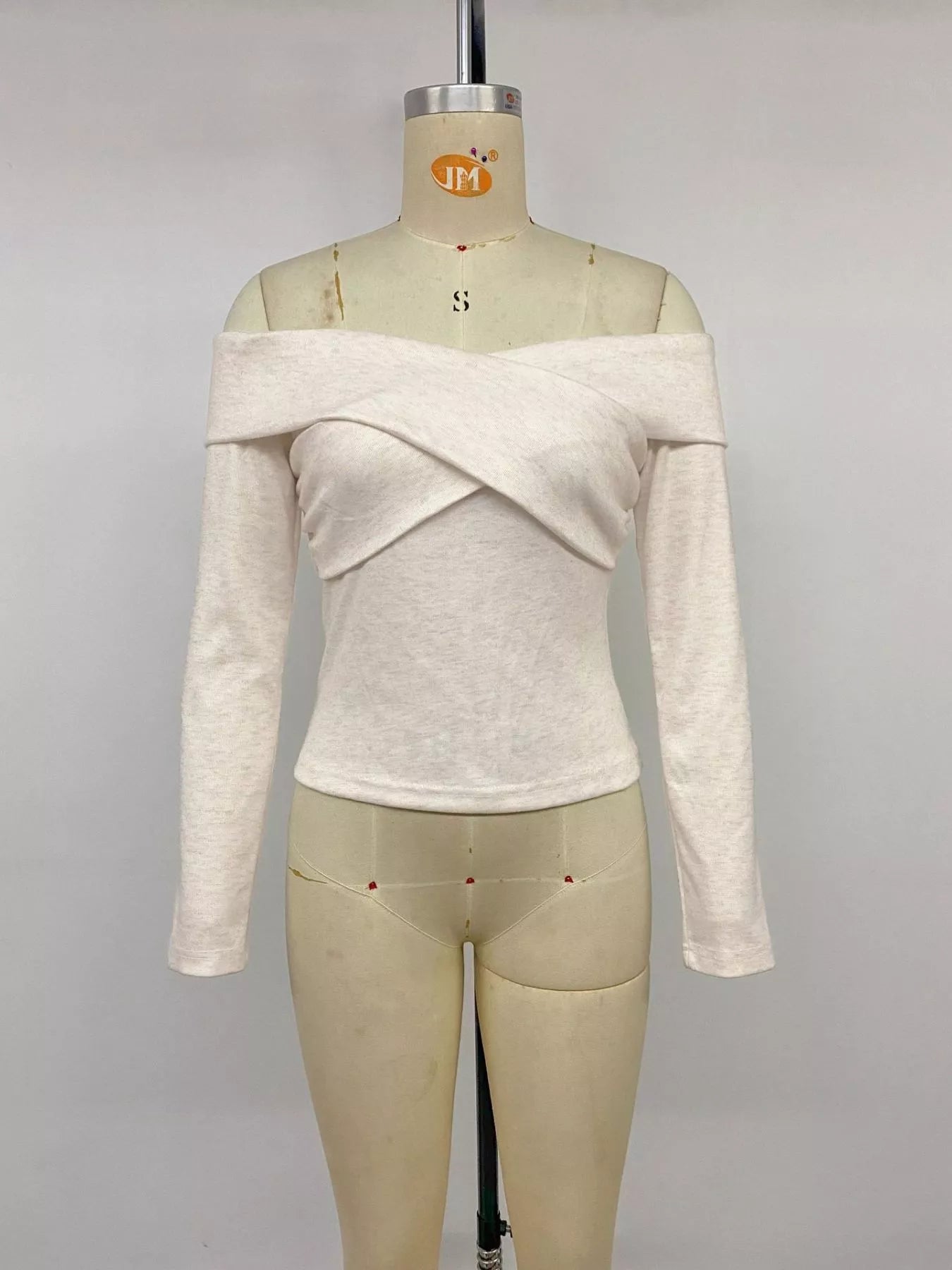 Apricot crisscross off-shoulder long sleeve top by Trendsi, featuring stylish design and fitted long sleeves.