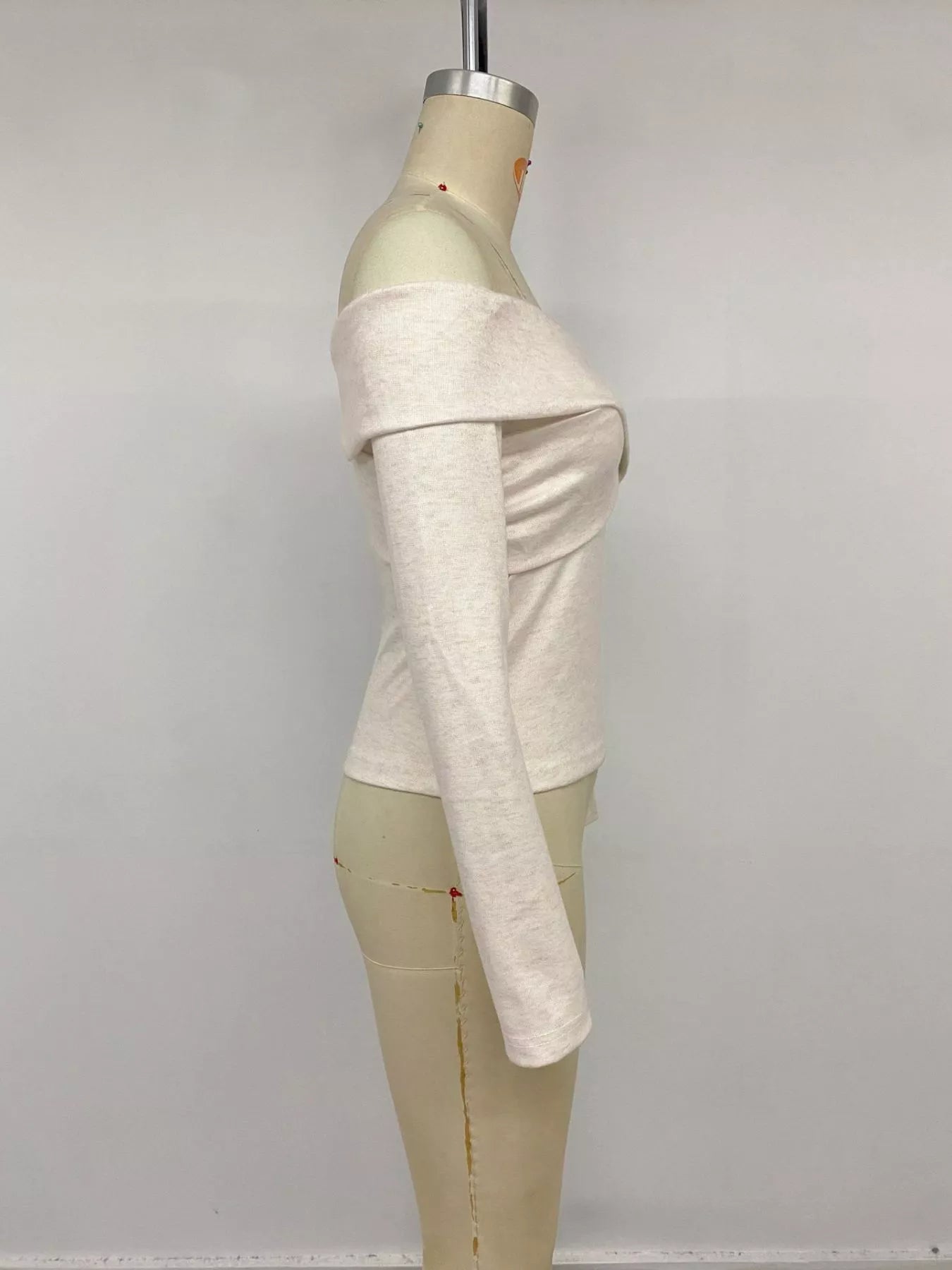 Apricot crisscross off-shoulder long sleeve top by Trendsi, featuring stylish design and fitted long sleeves.