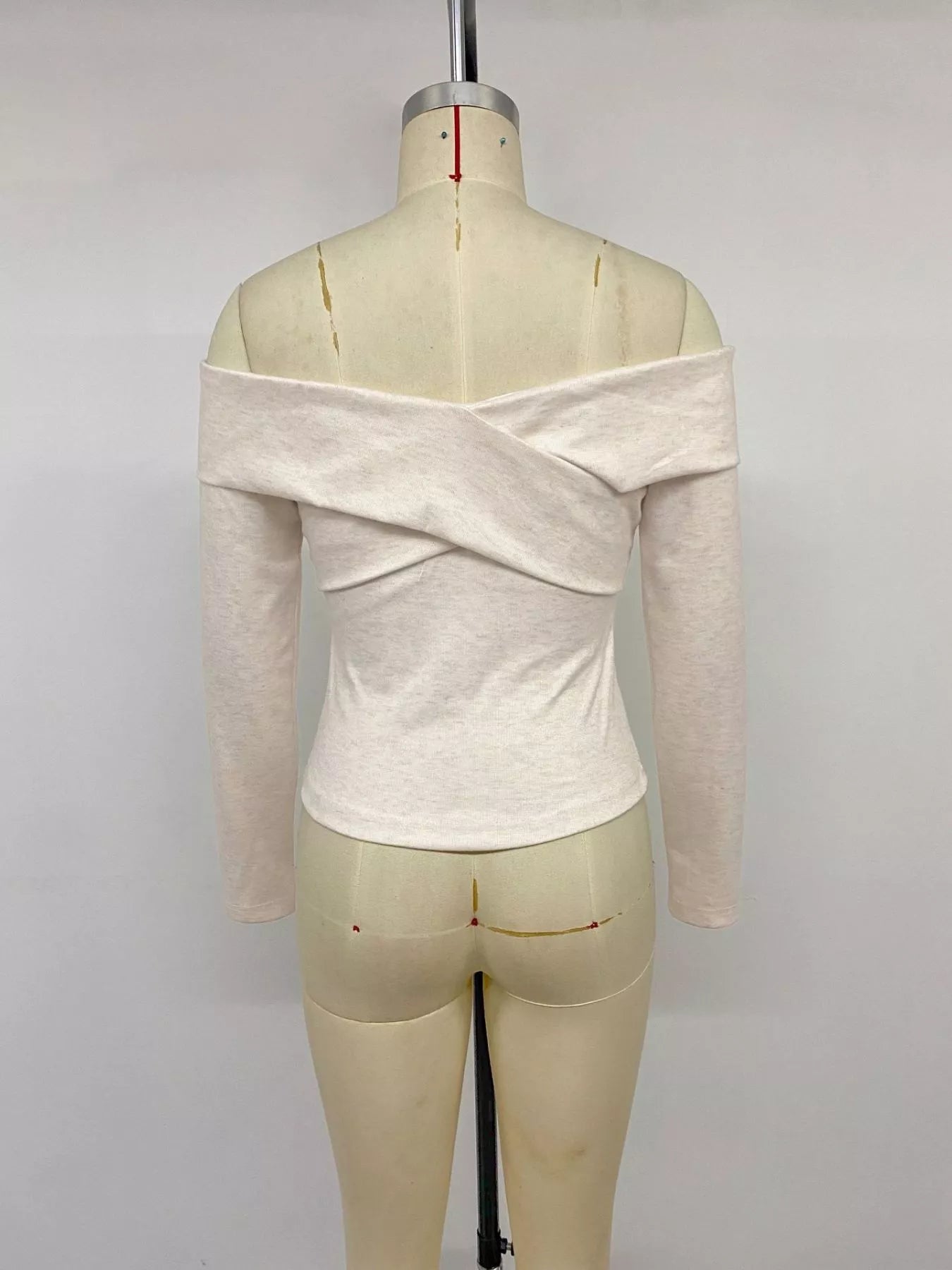 Apricot crisscross off-shoulder long sleeve top by Trendsi, showcasing a stylish neckline and fitted design on a model.