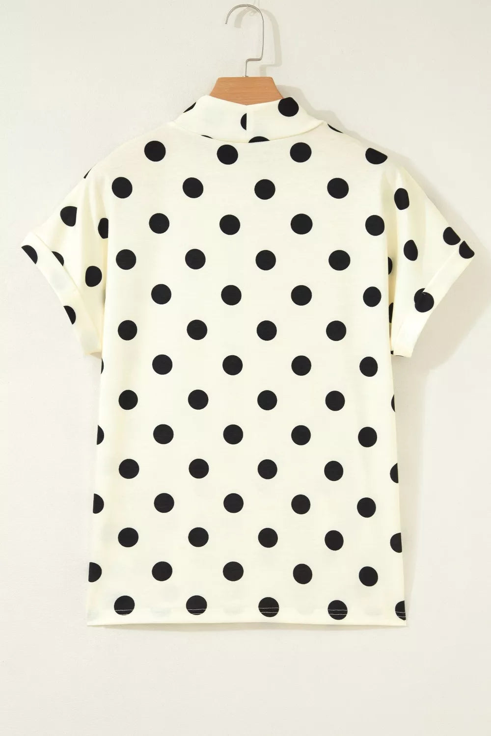 Beige polka dot mock neck short sleeve blouse by Trendsi, featuring a stylish design with a classic pattern and comfortable fit.