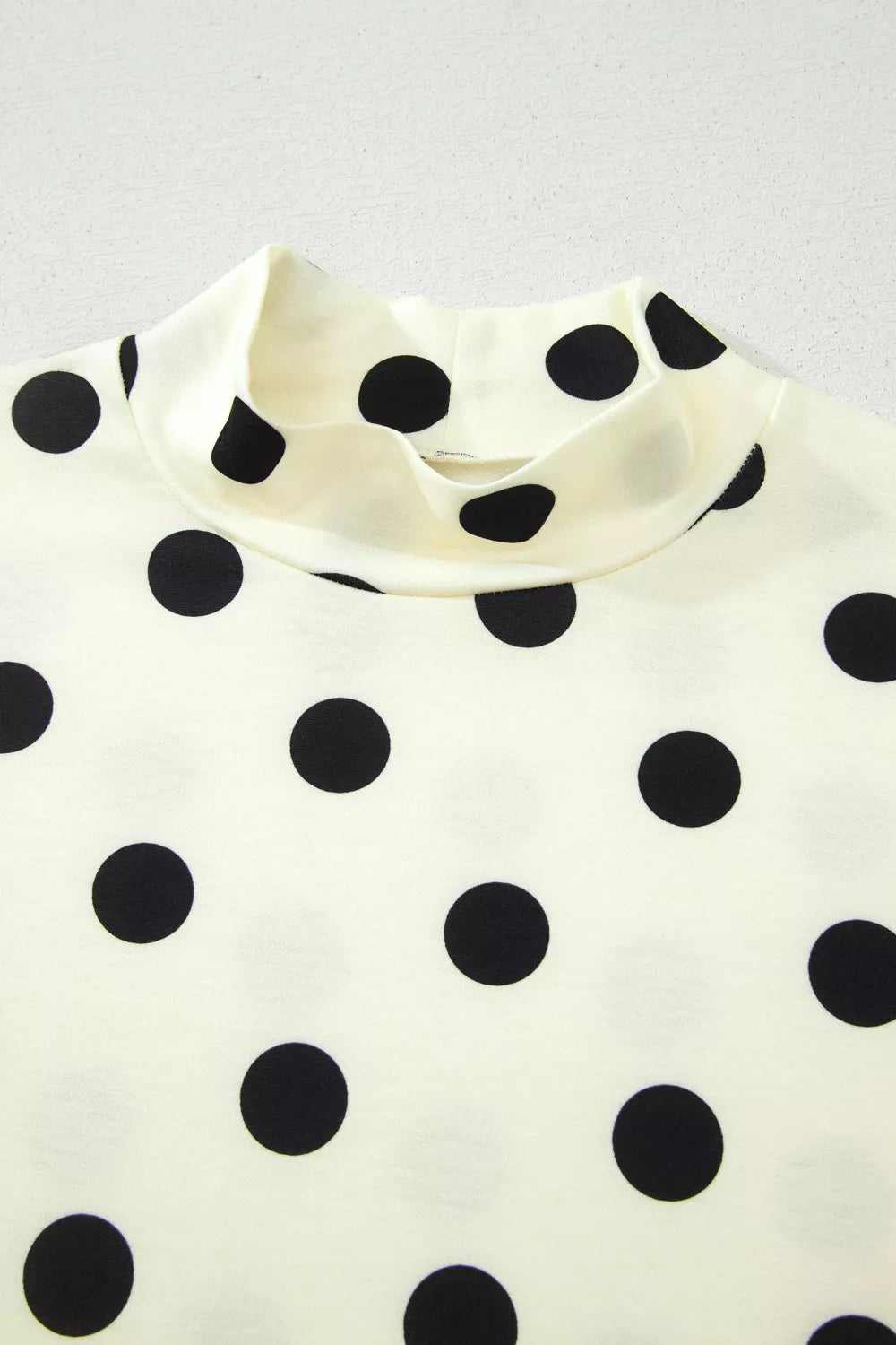 Beige polka dot mock neck short sleeve blouse by Trendsi, featuring a stylish design and comfortable fit.