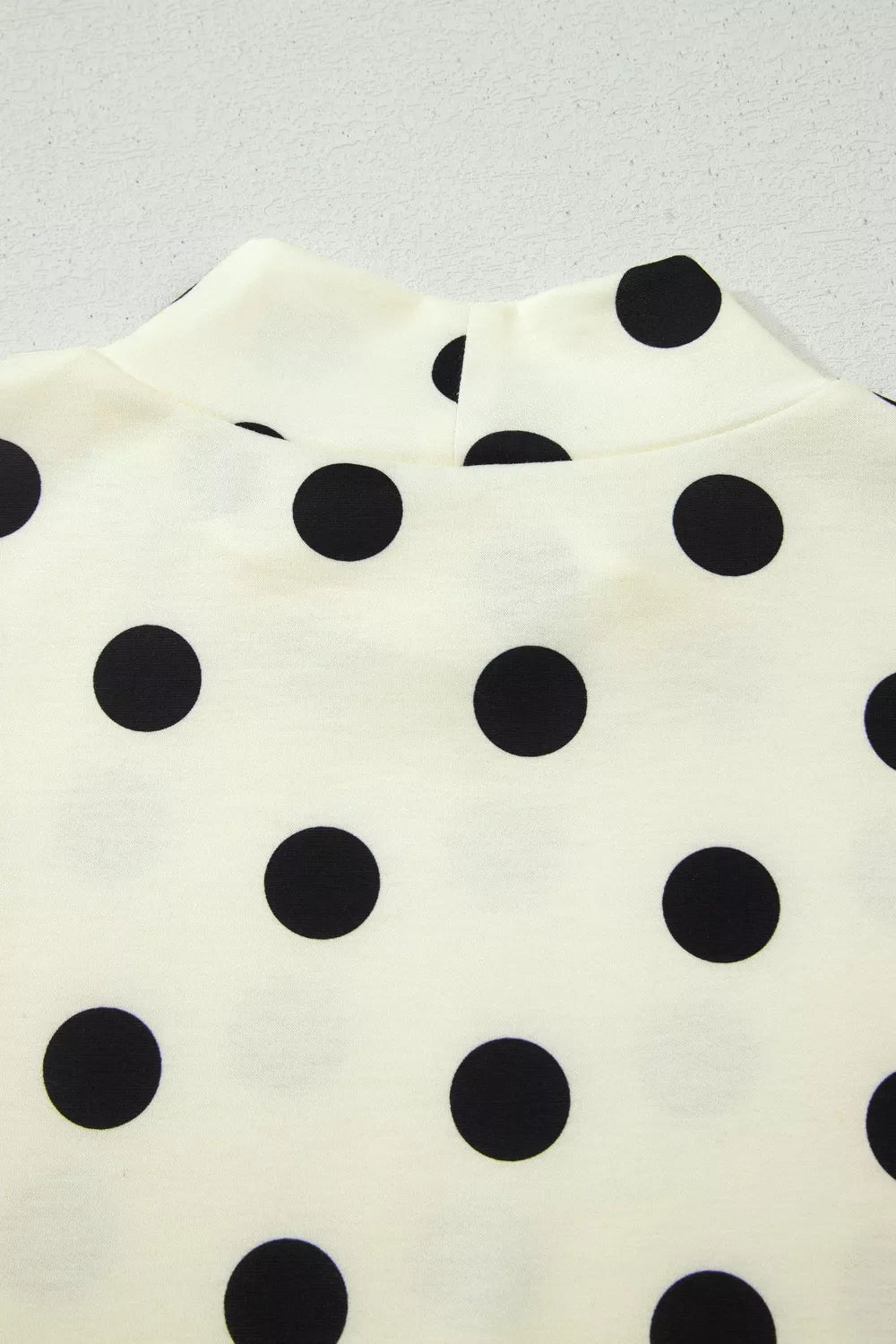 Beige polka dot mock neck short sleeve blouse by Trendsi featuring a stylish and comfortable design with a classic pattern.
