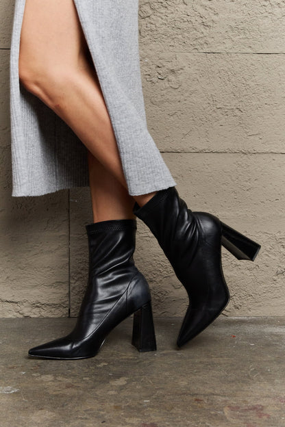 Black Weeboo Stacy sock boots with block heel and pointed toe, stylish ankle-height footwear by Trendsi.