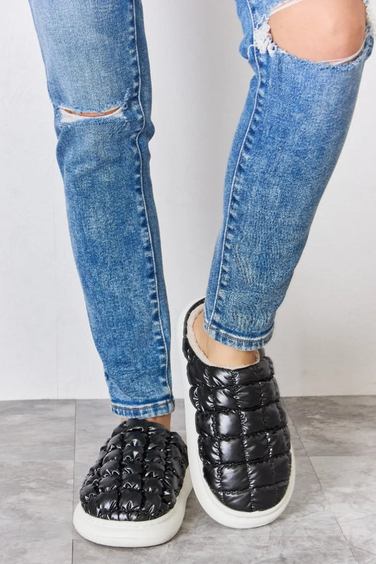 Black Melody Puffer Plush Slippers by Trendsi with padded, cozy design and slip-on style for comfortable indoor wear.