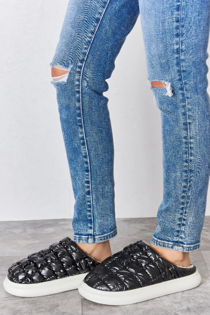 Black Melody Puffer Plush Slippers by Trendsi featuring cozy, padded design and soft plush material for comfortable indoor wear.