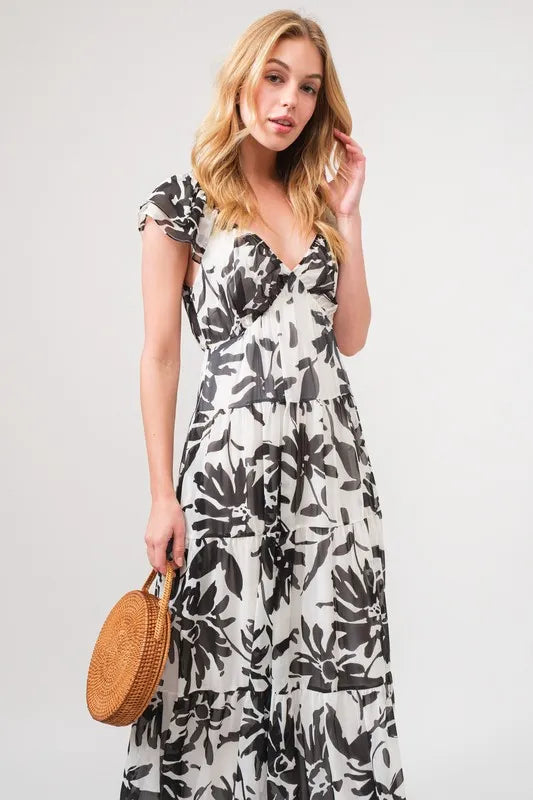 Black and cream tiered floral print maxi dress with ruffled sleeves from Trendsi, showcasing a flowing, elegant design.