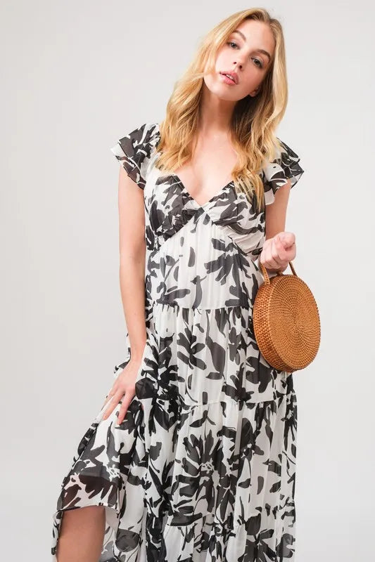 Black and cream tiered floral print maxi dress with ruffled sleeves from And The Why by Trendsi, featuring a flowing, elegant design.