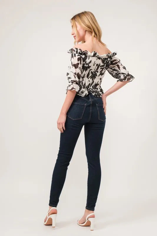 Black and cream floral printed off-shoulder top with smocked details from Trendsi's And The Why collection.