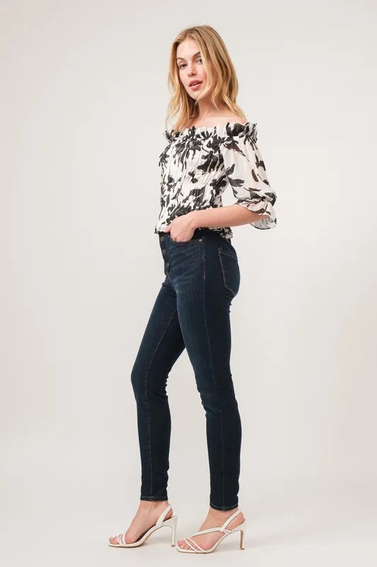 Black and cream floral printed smocked off-shoulder top by Trendsi, featuring a feminine off-shoulder neckline and floral pattern.