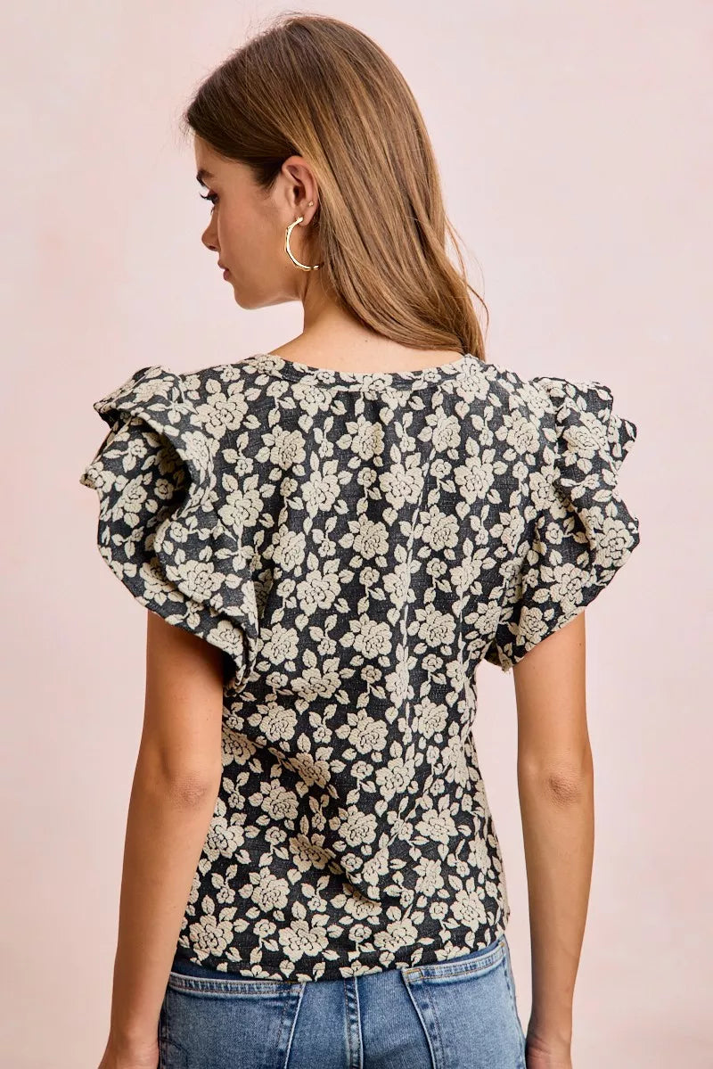 Black and light grey BiBi Floral Jacquard Knit Top with ruffle sleeves from Trendsi, showcasing intricate floral patterns and knit texture.