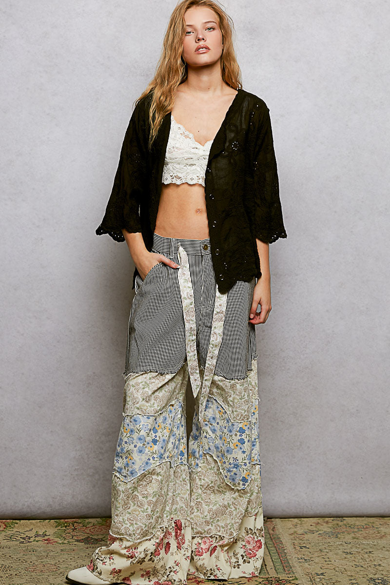Black floral eyelet V-neck shirt with scalloped hem from Trendsi, featuring a relaxed fit and eyelet detailing.