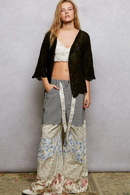 Black floral eyelet V-neck shirt with scalloped hem from Trendsi, featuring a relaxed fit and eyelet detailing.