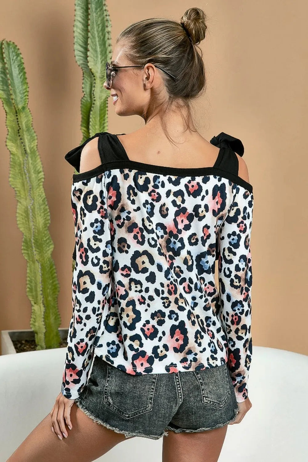 Black BiBi Leopard Shoulder Tie Long Sleeve Top by Trendsi featuring a stylish leopard print and shoulder tie design.