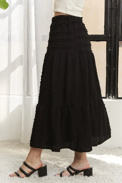 Black ADORA elastic waistband tiered midi skirt by Trendsi, featuring a flowy, layered design perfect for casual or dressy outfits.